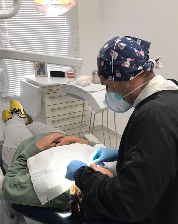 Dentista realizando atendimento em paciente na cadeira odontológica.